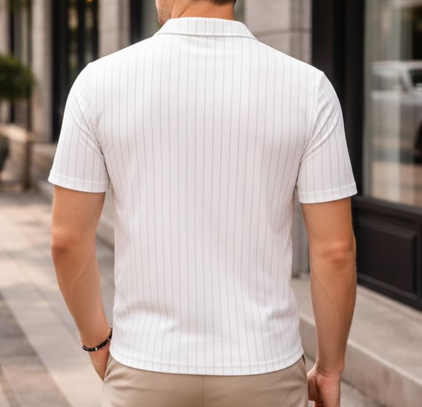 Man wearing a white ribbed polo shirt and beige pants walking on a city street.